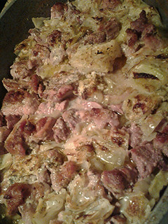 A picture of Cabbage, pork and cauliflower, with a sauce.