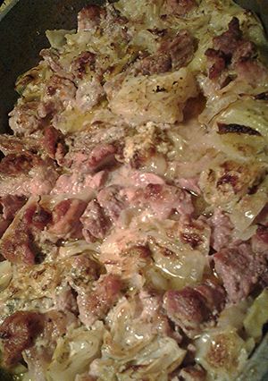 A picture of Cabbage, pork and cauliflower, with a sauce.