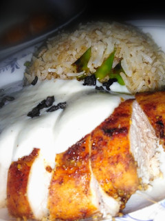 A picture of Chicken steak with chilli garlic rice and white sauce.