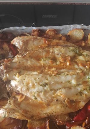 Una foto de Corvina al horno con patatas, cebollas y pimientos