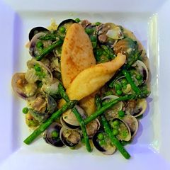 A picture of John dory with clams, asparagus, peas and parsley.