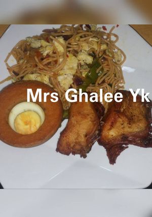 A picture of Jollof sphagetti with moimoi and fried chicken.