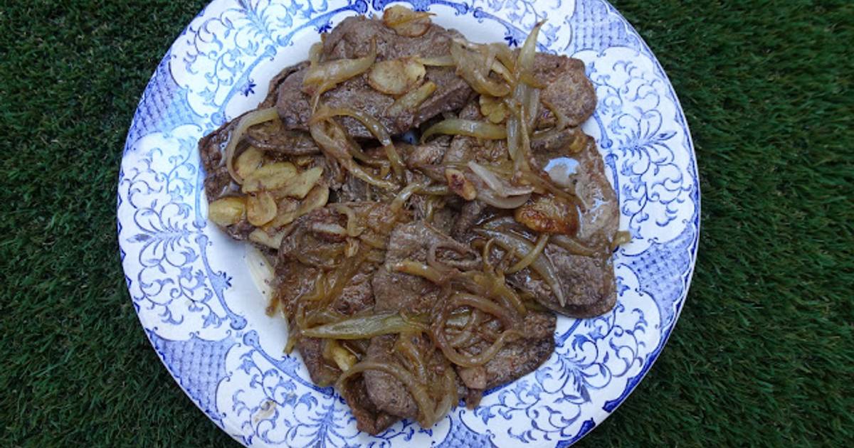 Fígado frito com cebola, batata doce e salada no prato branco