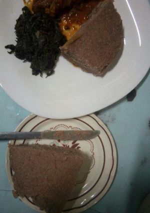A picture of Chicken stew, brown ugali and mchicha.