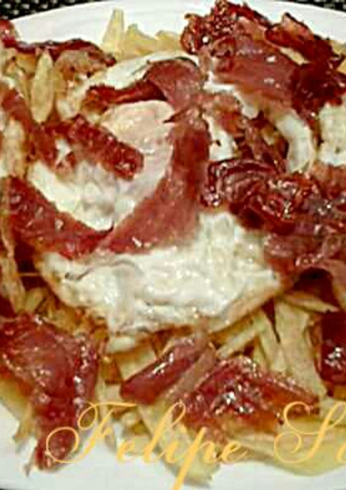 Una foto de Huevos rotos con patatas paja, y jamón serrano