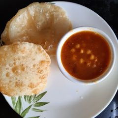 A picture of Chole bature or refined flour puris.