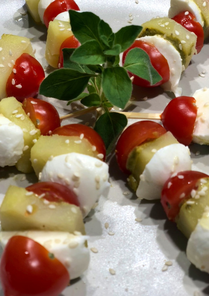 Una foto de Pintxitos papa, cherry y mozzarella con pesto y semillas de sésamo
