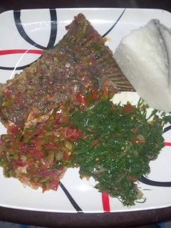 A picture of Wet fried fish, kales with Ugali.