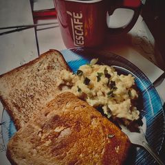 A picture of Scrambled eggs paired with toast and a cup of black coffee.