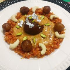 A picture of Stuffed cheese gulab jamun in carrot shahi rabri.