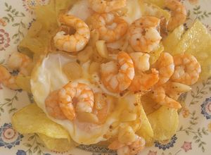 Una foto de Patatas chips con huevos fritos y gambas al ajillo