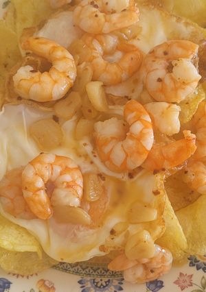 Una foto de Patatas chips con huevos fritos y gambas al ajillo