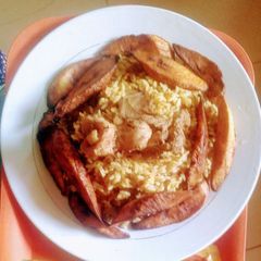 A picture of Jollof rice with cooked beef and fried plaintain.
