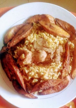 A picture of Jollof rice with cooked beef and fried plaintain.