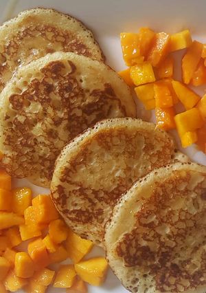 A picture of Pancakes With Mango Chunks & honey.