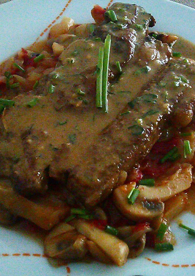 Una foto de Churrasco sobre lecho de champiñones y salsa de su mismo jugo