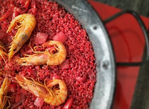 Una foto de Paella roja de sepia y gamba alistada con fumet de alga fucus y rape
