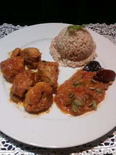 Una foto de Pollo con arroz servido con salsa de ciruelas, dátiles y pipas