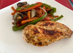 Una foto de Pollo a la plancha con base finas hierbas (papeles para cocción) acompañado de verduras salteadas