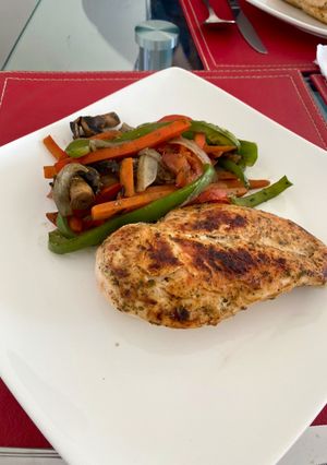 Una foto de Pollo a la plancha con base finas hierbas (papeles para cocción) acompañado de verduras salteadas