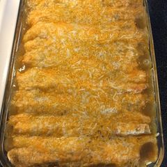 A picture of Chicken enchiladas with green sauce.