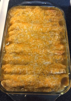 A picture of Chicken enchiladas with green sauce.