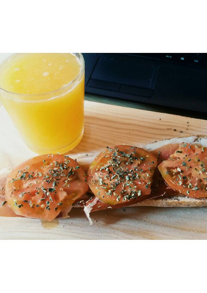 Una foto de Desayuno: Zumo de naranja y tostada con tomate y jamón serrano