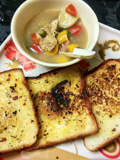 A picture of Chicken stew with garlic bread.