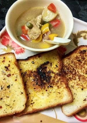 A picture of Chicken stew with garlic bread.