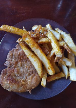 Una foto de Milanesas fritas acompañadas de papas rústicas al horno