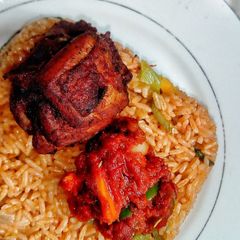 A picture of Ghanaian vegetable Jollof rice with red seasoned chicken.