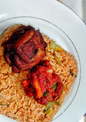 A picture of Ghanaian vegetable Jollof rice with red seasoned chicken.