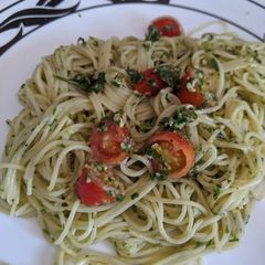 A picture of Pesto with angel hair pasta and grape tomatoes.