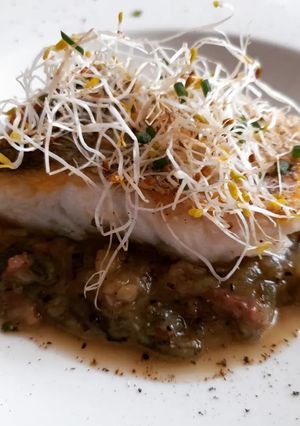 Una foto de Merluza a la plancha con salsa de calabacín y jamón al tomillo
