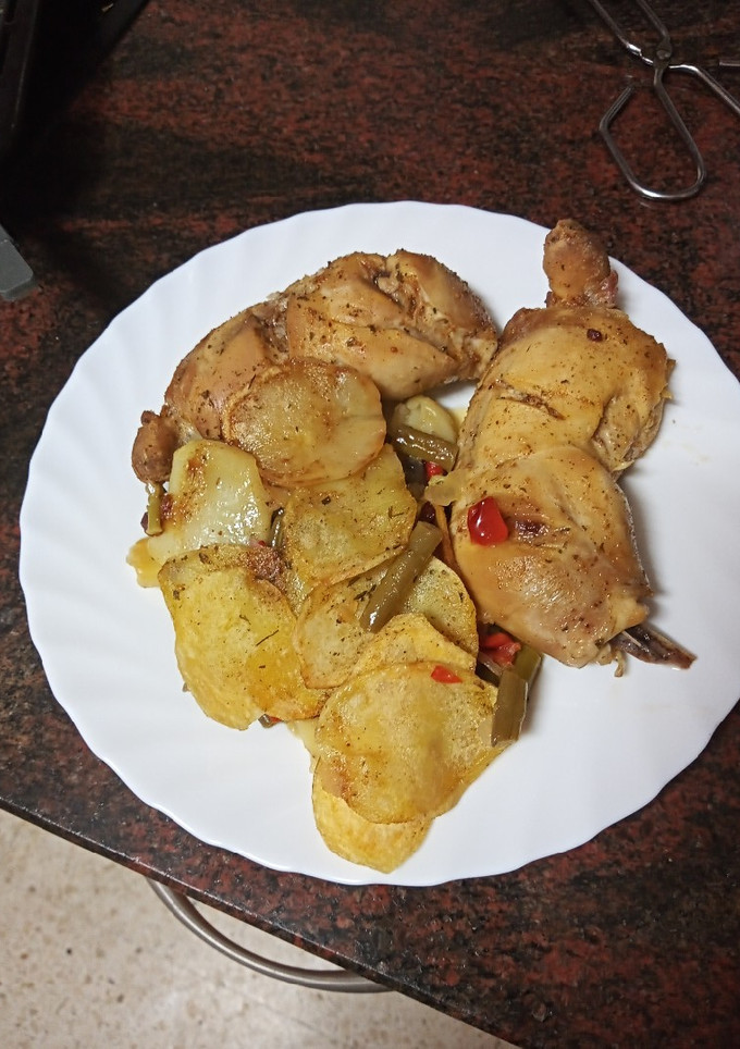 Una foto de Muslitos de pollo sobre cama de papas y verduras al horno