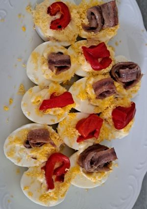 Una foto de Huevos rellenos de atún decorados con anchoa y pimiento rojo