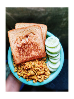 A picture of Scrambled eggs with brown bread and cucumber.