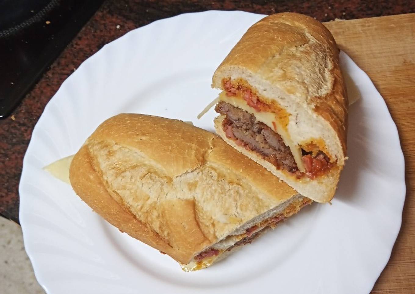 Bocadillo de bistec empanado, queso y salsa boloñesa