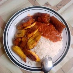 A picture of Boiled rice with fried plantain and pomo.