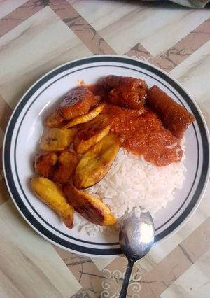 A picture of Boiled rice with fried plantain and pomo.
