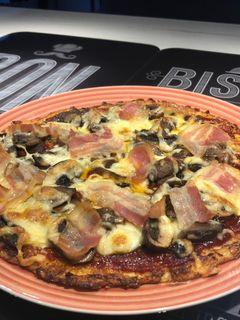 Una foto de Pizza de masa de coliflor con bacon y champiñones