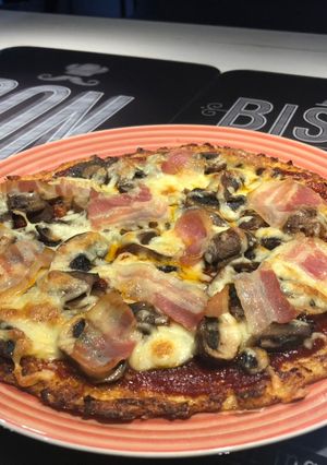 Una foto de Pizza de masa de coliflor con bacon y champiñones