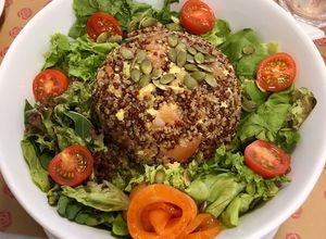 Una foto de Timbal de Quinoa 3 semillas con palta y salmón junto a lechuga, tomate cherry y semillas de zapallo