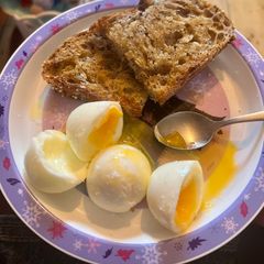 A picture of Soft boiled eggs, with a thick slice of buttered, malt seeded bread.