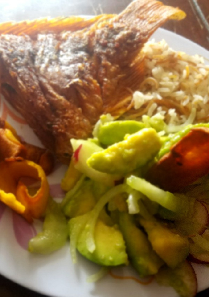 Una foto de Mojarra frita, ensalada, arroz y chips de plátano