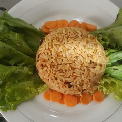 A picture of Jollof rice with carrots and lettuce.
