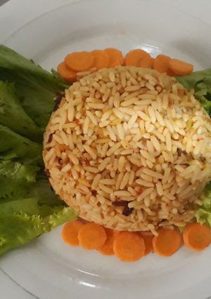 A picture of Jollof rice with carrots and lettuce.