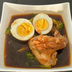 A picture of Chicken Wing and Veggies in Black Ramen Soup.