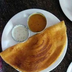 A picture of Masala dosa with sambhar and coconut chutney.