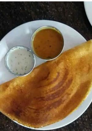 A picture of Masala dosa with sambhar and coconut chutney.